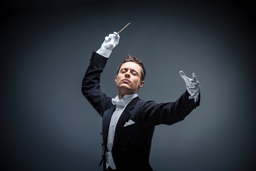 Young man in tuxedo conducting