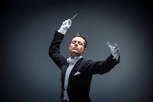 Composer Young man in tuxedo conducting musical conductor stock pictures, royalty-free photos & images