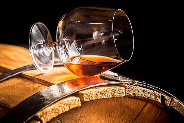 Glass of cognac on the vintage wooden barrel.