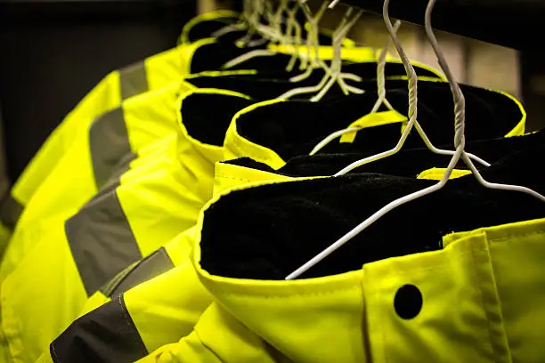 Yellow safety fluorescent jackets hanged up. Multiple jackets.