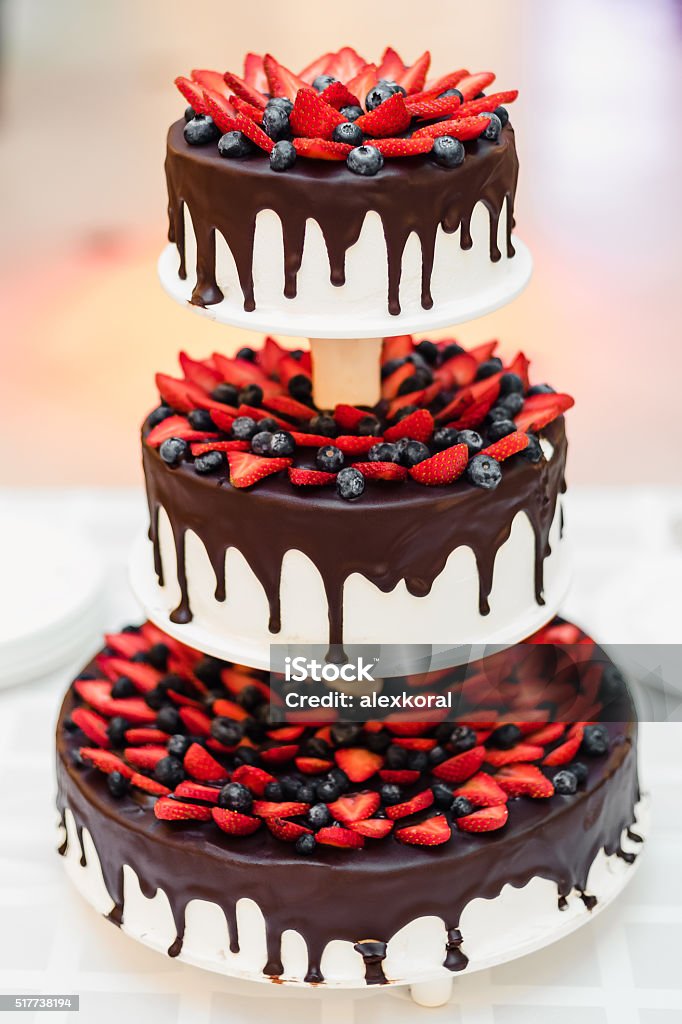 wedding cake with strawberries and blueberries in chocolate glaze delicious chocolate cake with strawberries and blueberries Baked Pastry Item Stock Photo