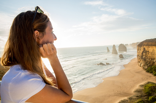 Young woman watches the sunset at the Twelve Apostles sea rocks on the Great Ocean Road in Victoria's state of Australia.