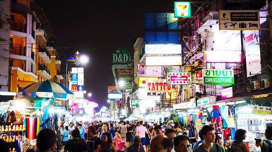 Khao San Road in Bangkok at night: You see many tourists walking around, having fun and enjoying their vacation
