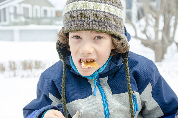 istock Young boy eating maple syrup taffy outside 517742036