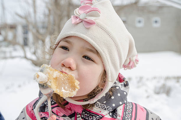 jeune fille manger du sirop d'érable bonbon à l'extérieur - maple syrup sugar shack photos et images de collection