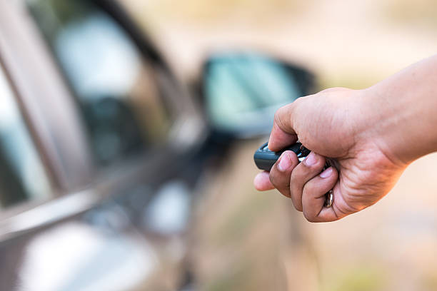 Man's hand pushing unlock button on car remote stock photo
