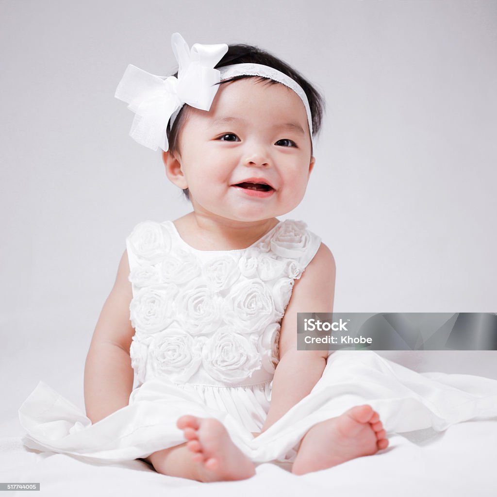 Baby smiling cute baby girl in white dress smiling for the camera 12-23 Months Stock Photo