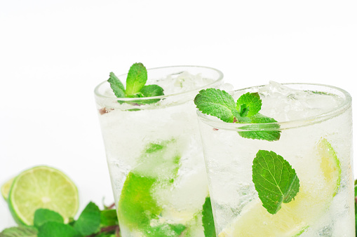 closeup two mojito cocktail with lime and mint in tumbler glass on white background