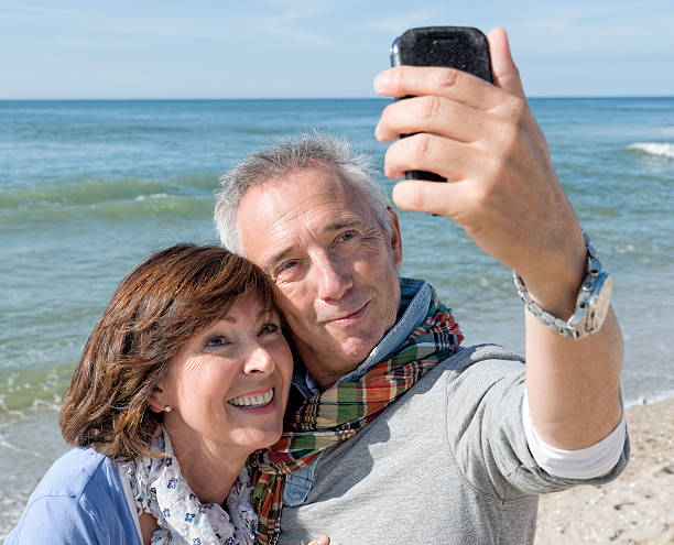 istock Laughing senior couple on beach making selfie with mobile 517746915