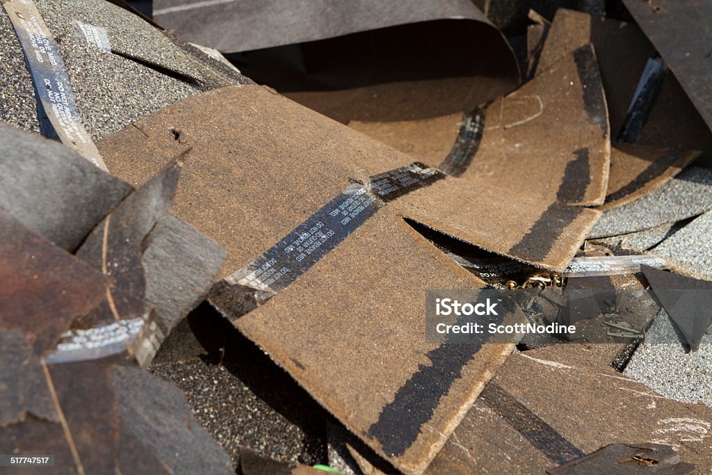 Old Discarded Asphalt Roof Shingles Trash Shallow depth-of-field shot of a trash pile of old asphalt roof shingles and tar paper removed during a residential house roof replacement. Wood Shingle Stock Photo