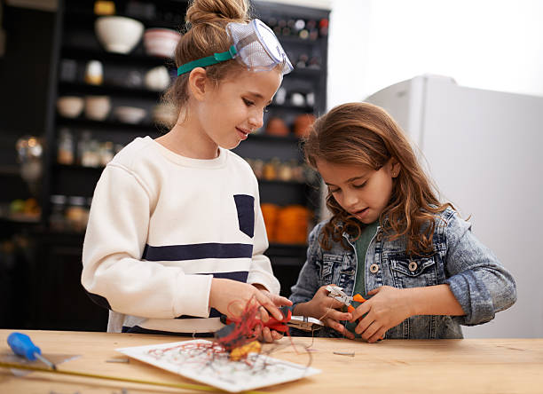 Fixing things together Shot of a two little girls helping each other make something creative with tools indoors girl with a hammer stock pictures, royalty-free photos & images