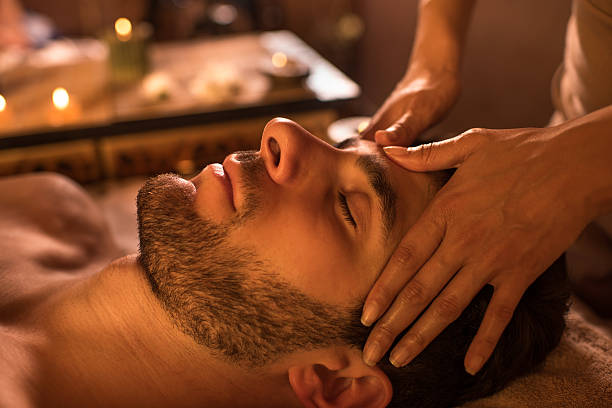 Close-up of a man receiving facial massage at the spa. Close-up of a man relaxing with eyes closed during head massage at the spa. facial massage stock pictures, royalty-free photos & images