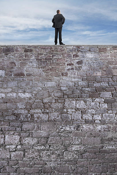 istock Businessman Standing and Looking on the High Stone Wall 517752908