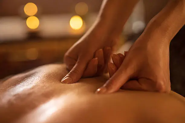 Close-up of massage therapist applying pressure on man's back at the spa.