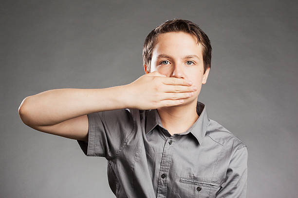 ragazzo adolescente su sfondo grigio sulla bocca con la mano - little boys shock surprise human mouth foto e immagini stock