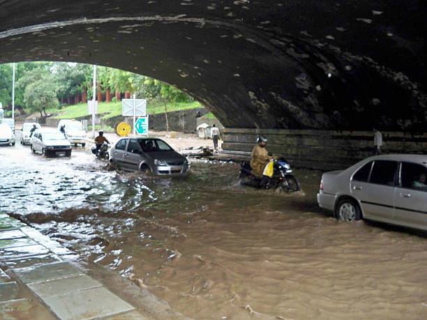 Floods in New Delhi New Delhi, India - January 4, 2008: People in motorcycles and vehicles driving on a flooded underpass. monsoon stock pictures, royalty-free photos & images