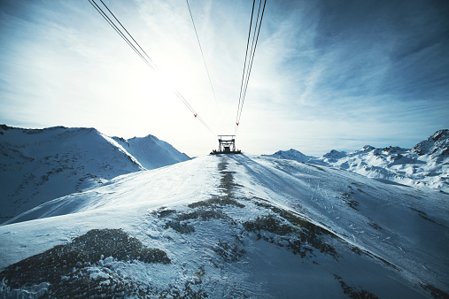 New modern spacious big cabin ski lift gondola against snowcapped forest tree and mountain peaks covered in snow landscape in luxury winter alpine resort. Winter leisure sports, recreation and travel.