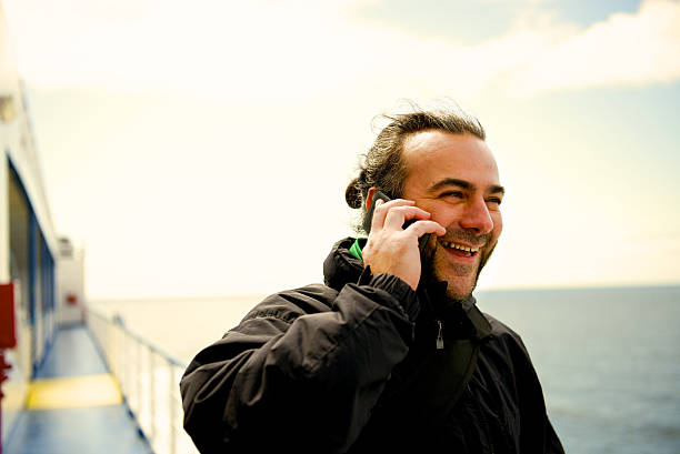 istock man in the ferry promenade deck,smiling at the mobil 517796501