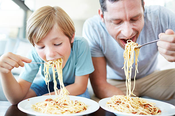 il est tellement comme son père - child eating pasta spaghetti photos et images de collection