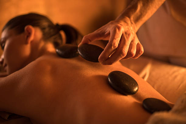 Close-up of hot stone therapy at the spa. Close-up of massage therapist placing stones on woman's back during lastone therapy at the spa. hot stone massage stock pictures, royalty-free photos & images