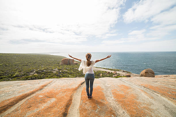 Beauty in nature, getting away from it all Cheerful young woman arms outstretched at The Remarkable rocks, located in Flinder's  chase National park on Kangaroo Island, SA, Australia. flinders chase national park stock pictures, royalty-free photos & images