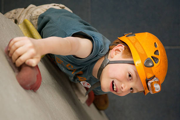 jovem garoto em uma parede de escalada na rocha - climbing wall rock climbing holding reaching - fotografias e filmes do acervo