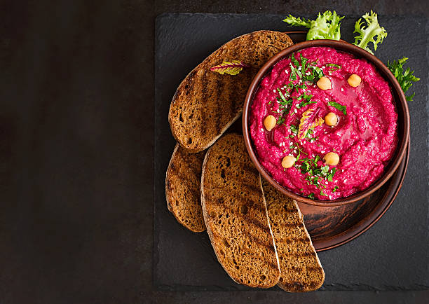 Roasted Beet Hummus with toast in a ceramic bowl Roasted Beet Hummus with toast in a ceramic bowl on a dark background. Top view food styling stock pictures, royalty-free photos & images