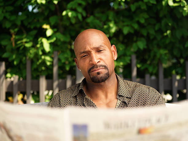 istock mature african american man reading newspaper 517798361