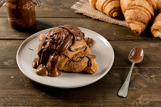 Sweet croissant with chocolate on rustic background stock photo