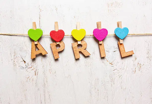 the word "april"  letters on a wooden clothespins on a white background old