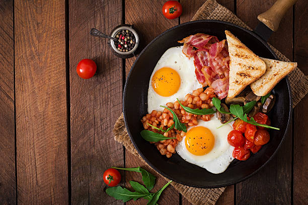 English breakfast - fried egg, beans, tomatoes, bacon and toast.