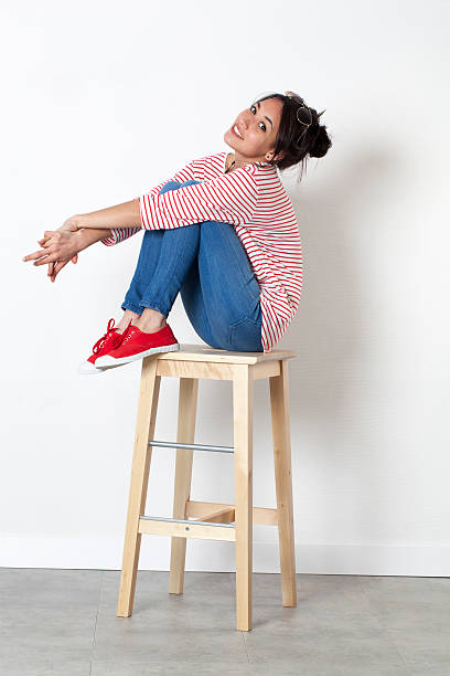istock relaxed young ethnic girl sitting on stool with legs crossed 517809236