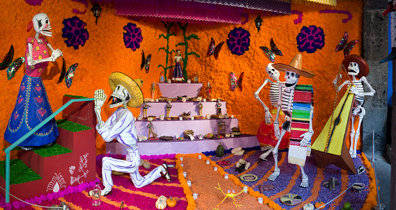 Mexico City, Mexico - October 31, 2012: Traditional Mexican life-size Dia de Muertos (Day of the Dead - All Saints) altar with sugar skulls and candles. The altar is made from paper mache and decorated with various grains and flowers.