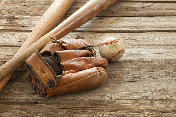 istock Old baseball, mitt and bats on rough wood surface 517816153