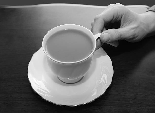 istock Woman picking up a cup of tea from a table 517832583