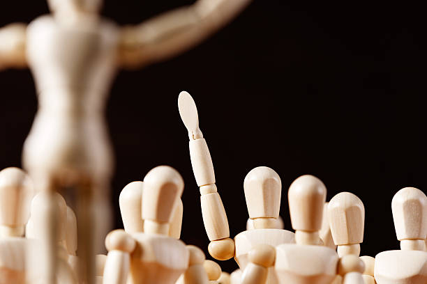 istock One puppet among many raises hand, responding or a volunteer 517833575