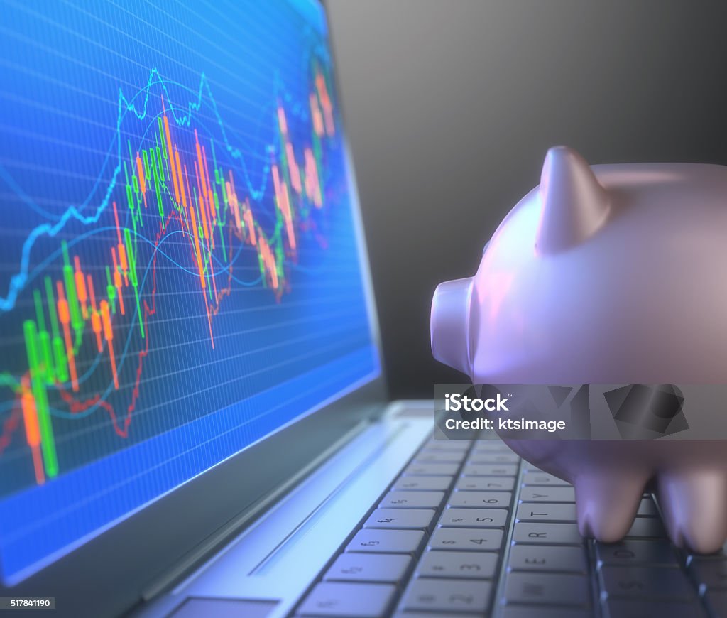 Robot Trading System And Piggy Bank Piggy bank on laptop keyboard looking at the chart of the stock market. Financial Technology Stock Photo