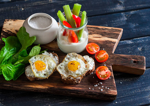 Sandwiches with cheese and quail eggs, Greek yogurt, celery, pepper Sandwiches with cheese and fried quail eggs, fresh herbs and cherry tomatoes, Greek yogurt, celery and pepper. Healthy breakfast or snack. On a wooden rustic board egg cherry tomato rye stock pictures, royalty-free photos & images