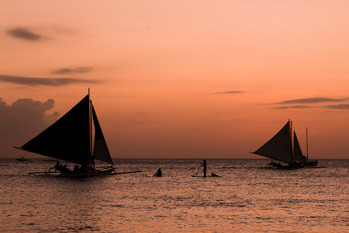 Two Boats and two mens silhouette in the ocean.