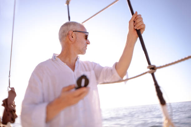 istock Mature man with compass looking at horizon from his yacht 517846496