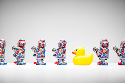 Retro tin toy robots and a rubber duck standing in a row.