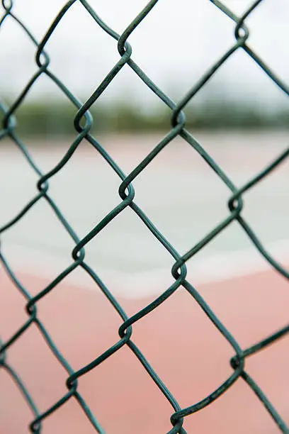 Close-up of a chain-link fence. on the other side is a sport ground.