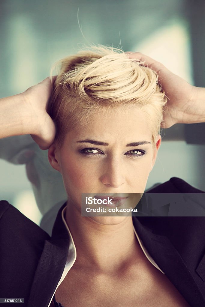 short hair blonde woman young blue eyes woman with trendy short blonde hair  outdoor portrait recline on glass window hands in hair Adult Stock Photo