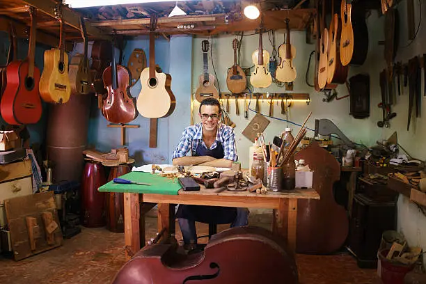 Photo of Portrait Of Happy Artisan Lute Maker In Guitar Shop Smiling