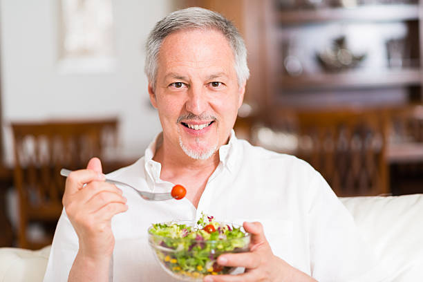 istock Smiling mature man eating a salad at home 517853388