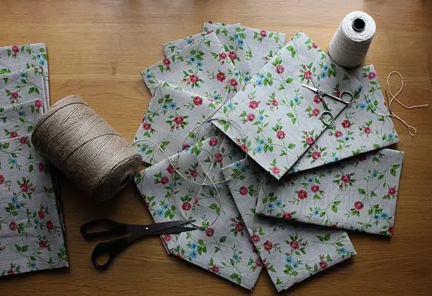 Linen towels with flower ornaments ready to be packed.Threads and scissors for crafting presents.