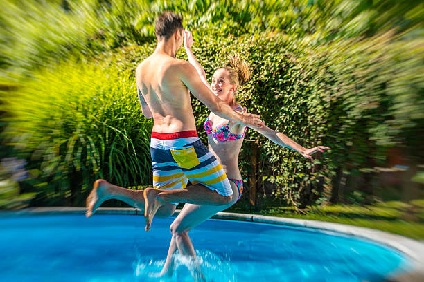 istock Young adult couple jumping into a pool 517870286