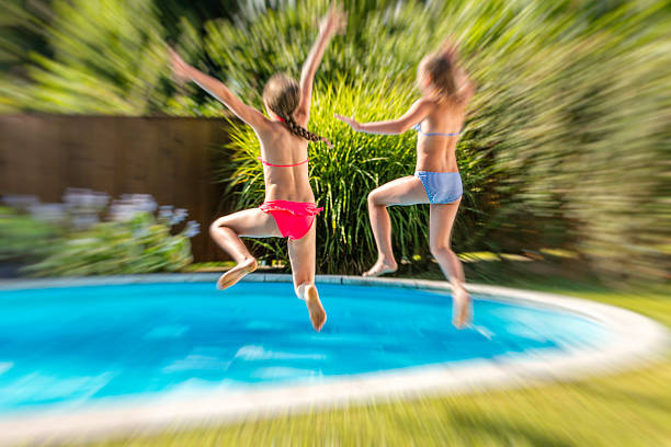 istock Two girls jumping into a pool 517870788
