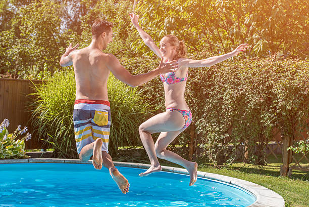 istock Young adult couple jumping into a pool 517870912