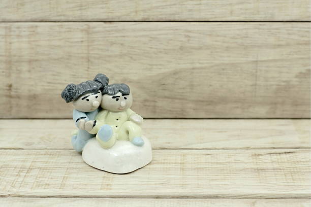 istock Little boy and girl ceramic dolls on wood pattern background 517871490